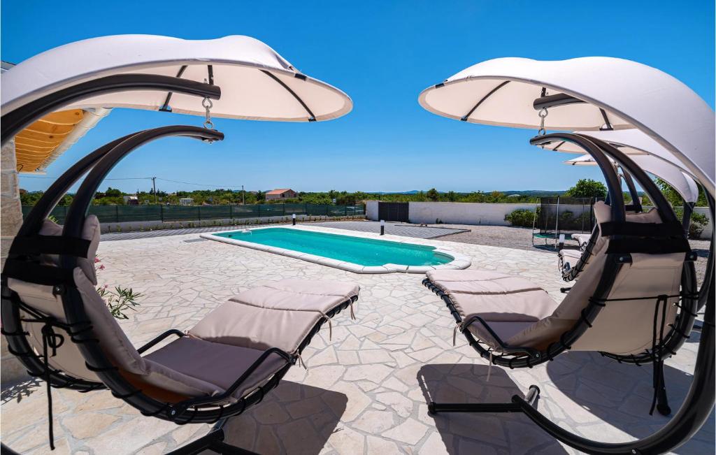 patio z 2 krzesłami, parasolem i basenem w obiekcie Nice Home In Zemunik Donji With Wifi w mieście Malić