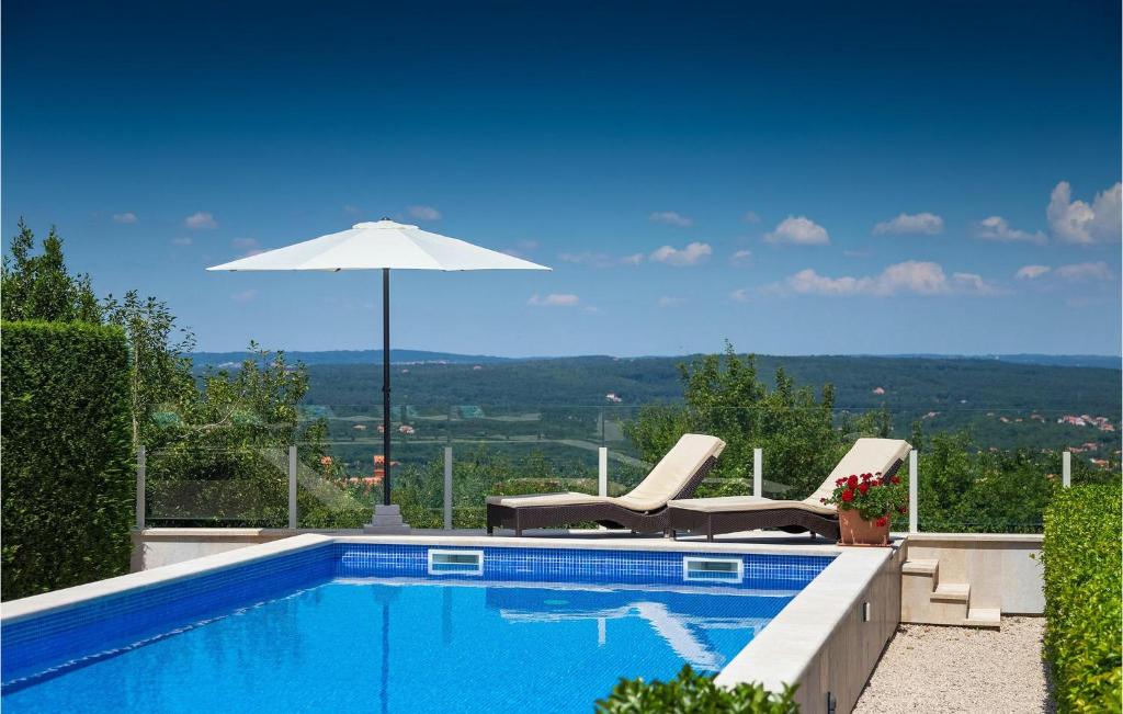 a swimming pool with two chairs and an umbrella at Villa Rosa Labin in Labin