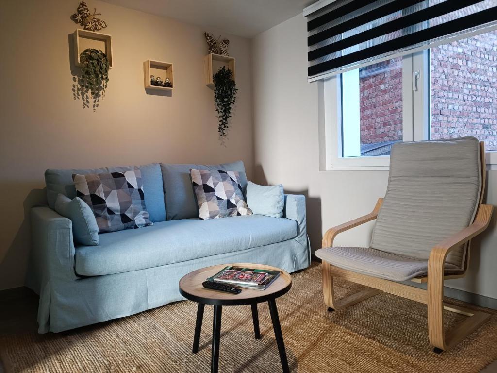 ein Wohnzimmer mit einem blauen Sofa und einem Sessel in der Unterkunft Au ptit Hottonruy in Stavelot