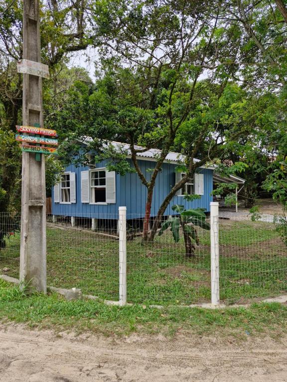 a blue house behind a fence with a tree at Casinha Trilha da Guarda in Guarda do Embaú