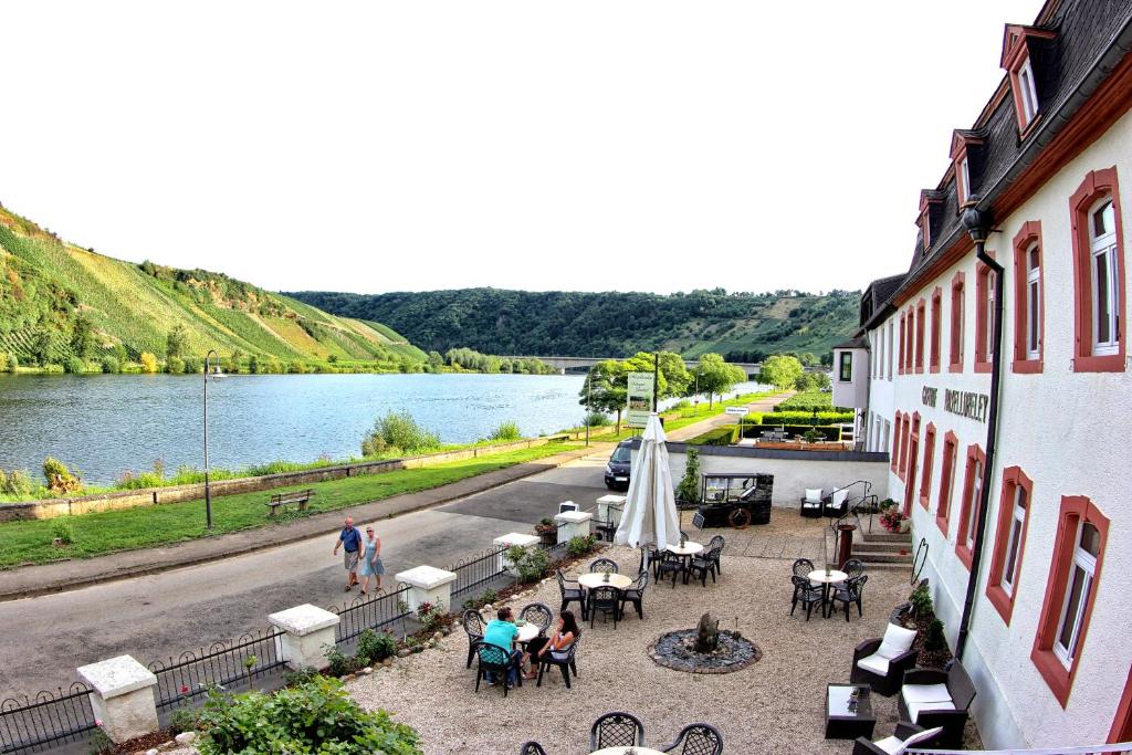 a building with tables and chairs next to a river at Hotel- Weingut- Moselloreley in Piesport