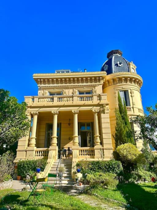 un grand bâtiment jaune avec une horloge en haut dans l'établissement Appartement exceptionnel belle époque avec grande terrasse plein sud, à Nice