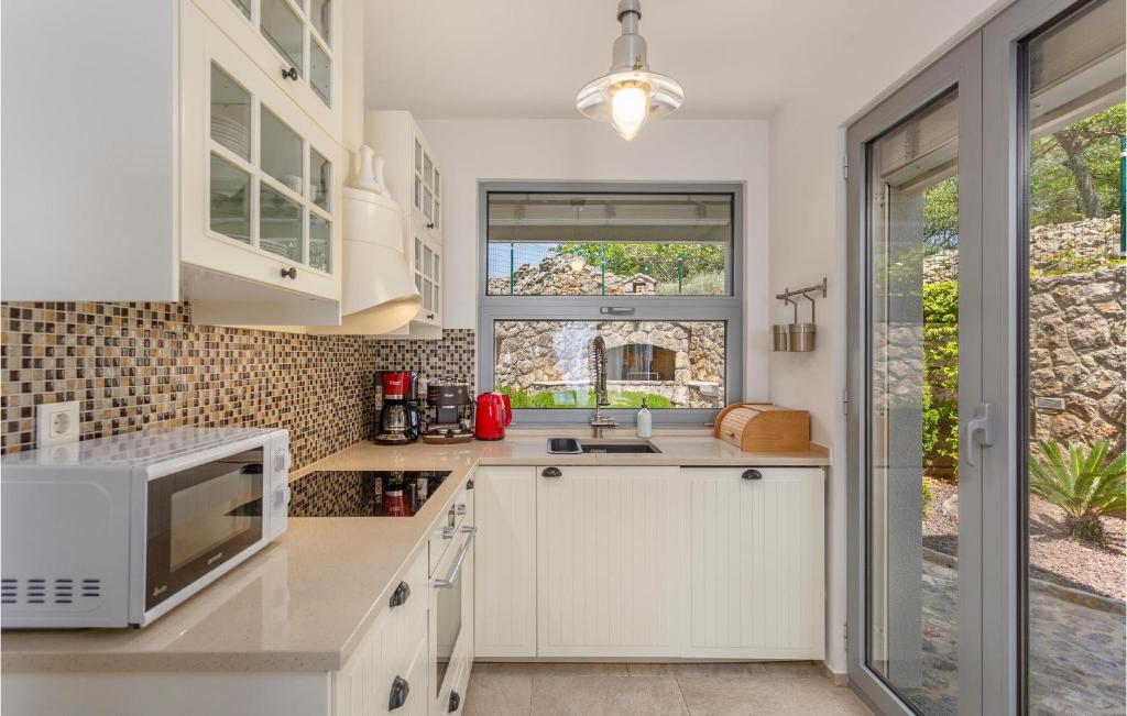 kuchnia z białymi szafkami i mikrofalówką w obiekcie 3 Bedroom Cozy Home In Krk w Krku
