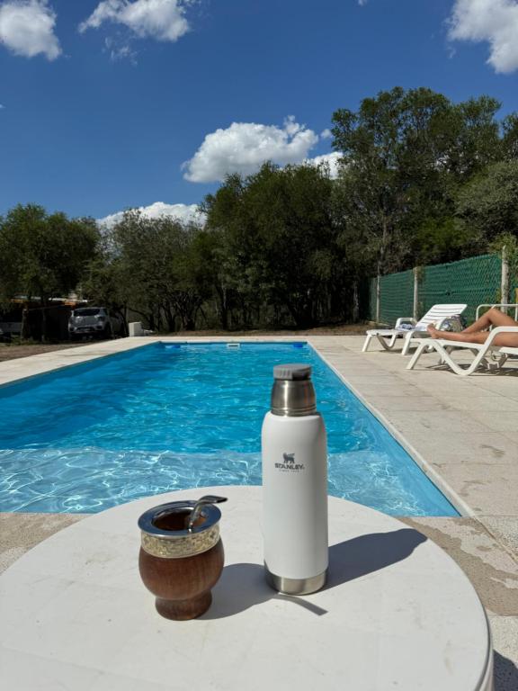a water bottle and a bowl next to a swimming pool at Altos de Las Sierras in Cosquín