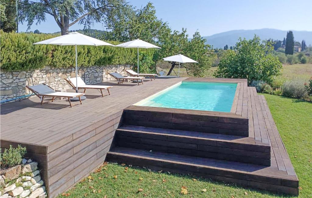 einen Pool mit Bänken und Sonnenschirmen auf einer Terrasse in der Unterkunft Cozy Apartment In Rignano Sull'arno in Rignano sullʼArno