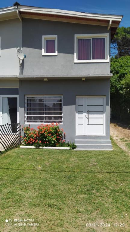 a house with white doors and flowers in the yard at Departamento Rosales Nro 2 in Valeria del Mar