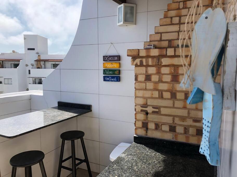 a kitchen with stools and a wall with a fish on it at Belíssima cobertura duplex com vista para o mar in Arraial do Cabo