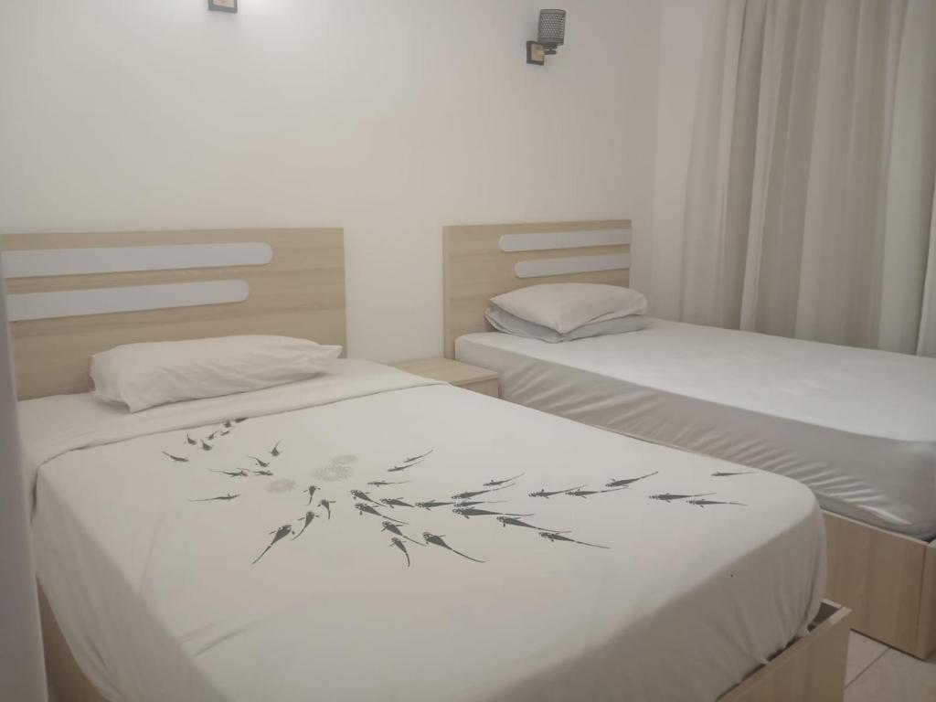 two beds in a small room with white sheets at 3 Zimmerwohnung mit 13 Pools in Sharm El Sheikh