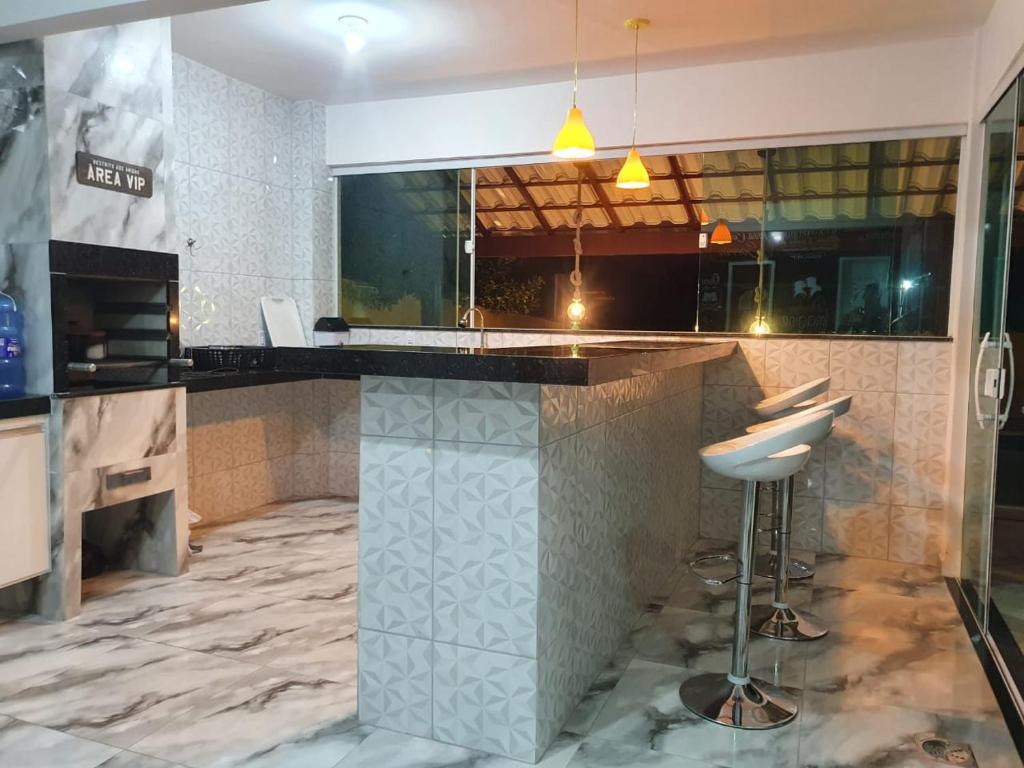 a kitchen with a counter and a bar with a stool at Casa de praia na Reserva do Peró em Cabo Frio - familiar com piscina in Cabo Frio