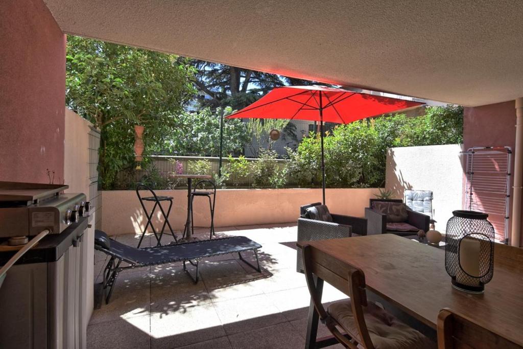 d'une terrasse avec une table et un parasol rouge. dans l'établissement Marina les calanques, à Marseille