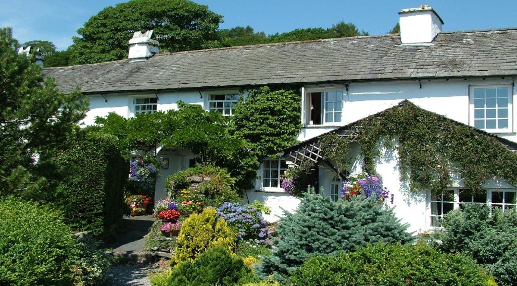 a white house with flowers in the front yard at Wheelgate in Torver