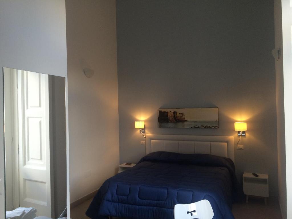 Base Napoli Mergellina في نابولي: غرفة نوم بسرير ازرق وعليها انارتين