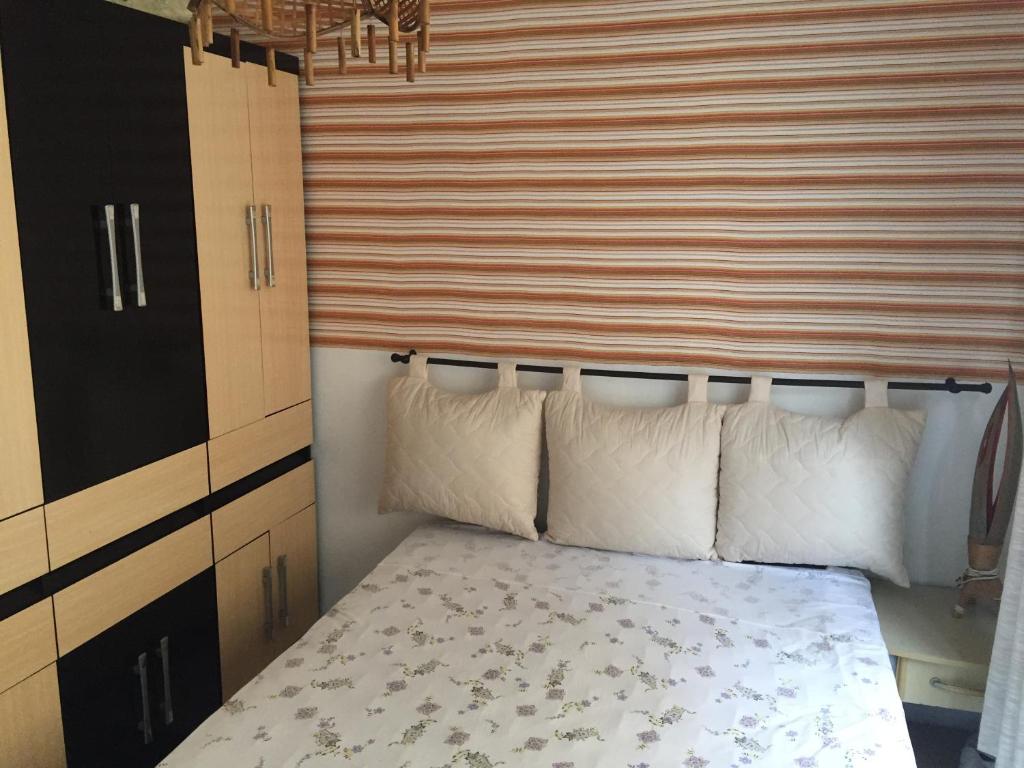 a bedroom with a bed with pillows and a striped wall at Apartamento Barra Velha in Barra Velha