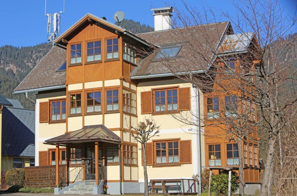 a large brown and white house with mountains in the background at Haus Leopold in Gosau