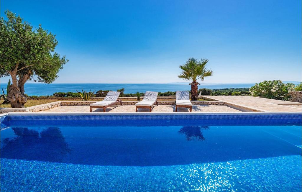 a swimming pool with two chairs and the ocean at Villa Toma in Škunca