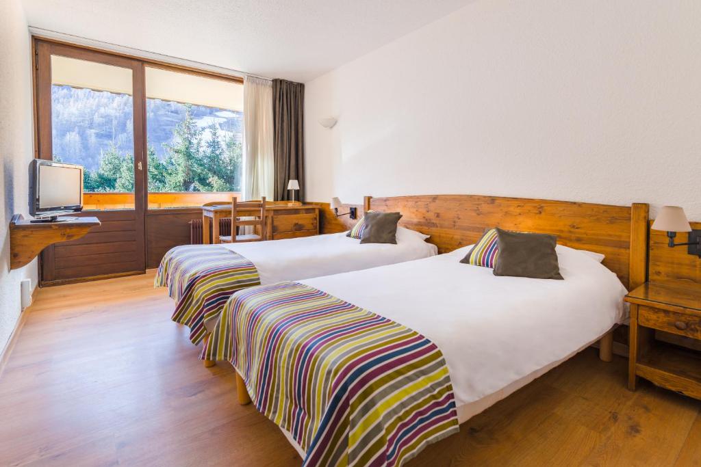 a bedroom with a large bed and a large window at Hôtel Plein Sud et piscine *** in Saint-Chaffrey