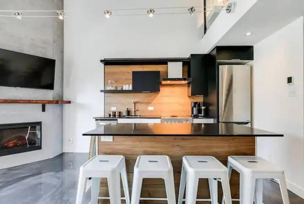 eine Küche mit einer schwarzen Theke und Hockern in der Unterkunft Condo moderne, escapade vacance, vue sur montagnes in Mont-Tremblant