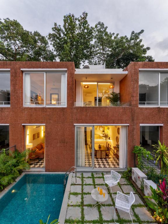 a brick house with a swimming pool in front of it at La Verona by The Blue Kite - 2 & 3 BHK Villas in Assagao with Private Pool, Garden, Caretaker, Kitchen & Security in Assagao