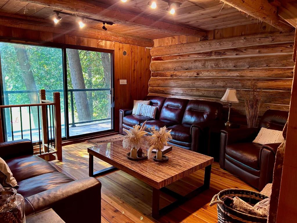 ein Wohnzimmer mit Ledermöbeln in einer Blockhütte in der Unterkunft John Wayne Cedar Oasis in Cookstown
