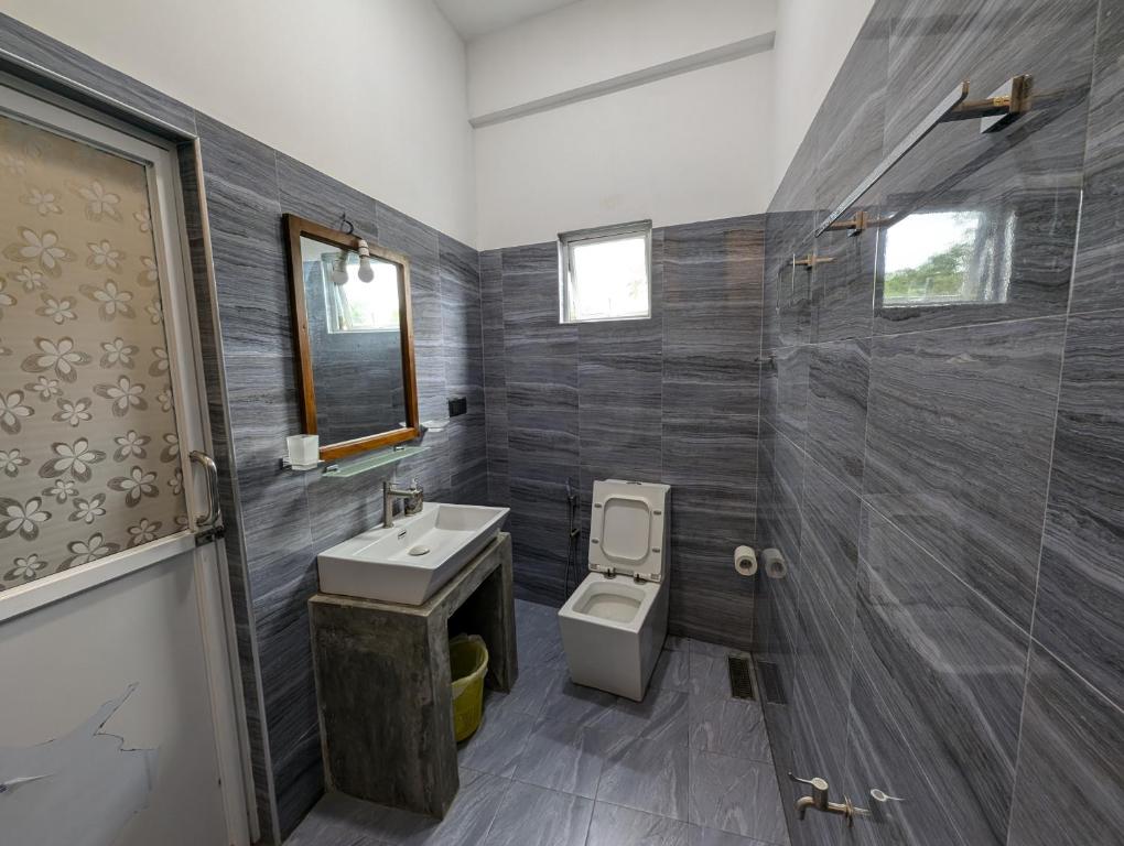 a bathroom with a toilet and a sink and a shower at Costels Mirissa in Mirissa