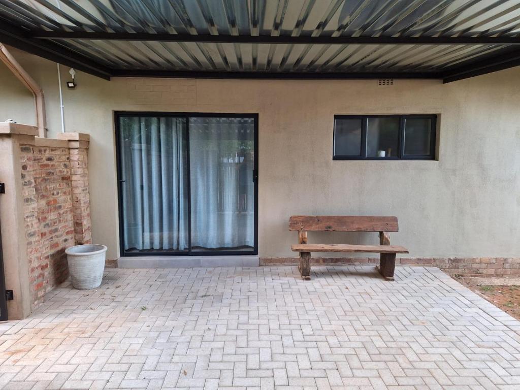 una panca di legno seduta di fronte a un edificio di The Guestroom a Klerksdorp