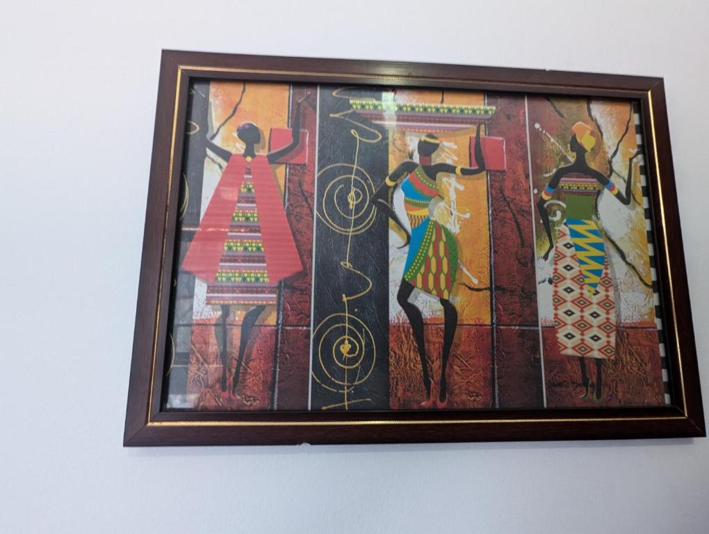 a framed painting of women on a wall at Costels Mirissa in Mirissa