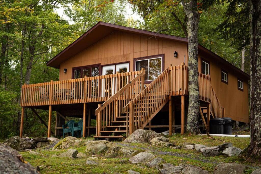 a cabin in the woods with a large wooden deck at Lakeside 2 Bedroom Wolfs Den Cabin On Kab in Kabetogama