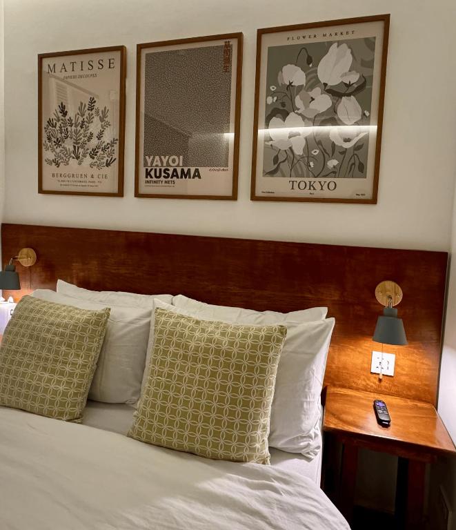 a bedroom with a bed with three pictures on the wall at Cozy Cottage in Kabankalan