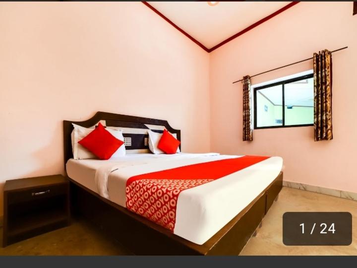a bedroom with a bed with red pillows and a window at Jyotis home stay Khajuraho in Khajurāho