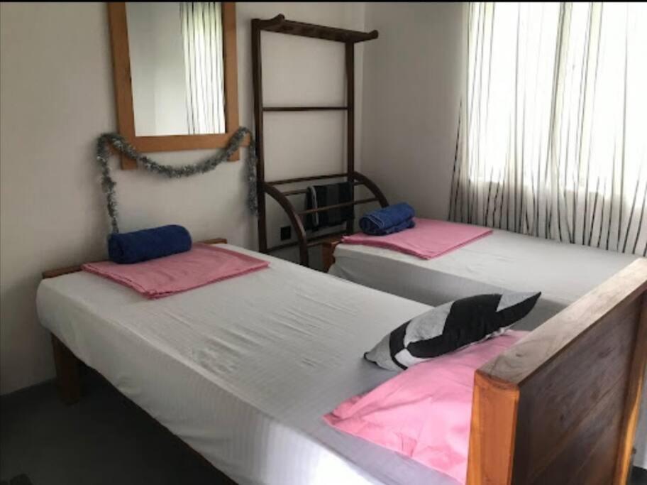 two beds in a room with pink and black sheets at Villa Amorino in Galle