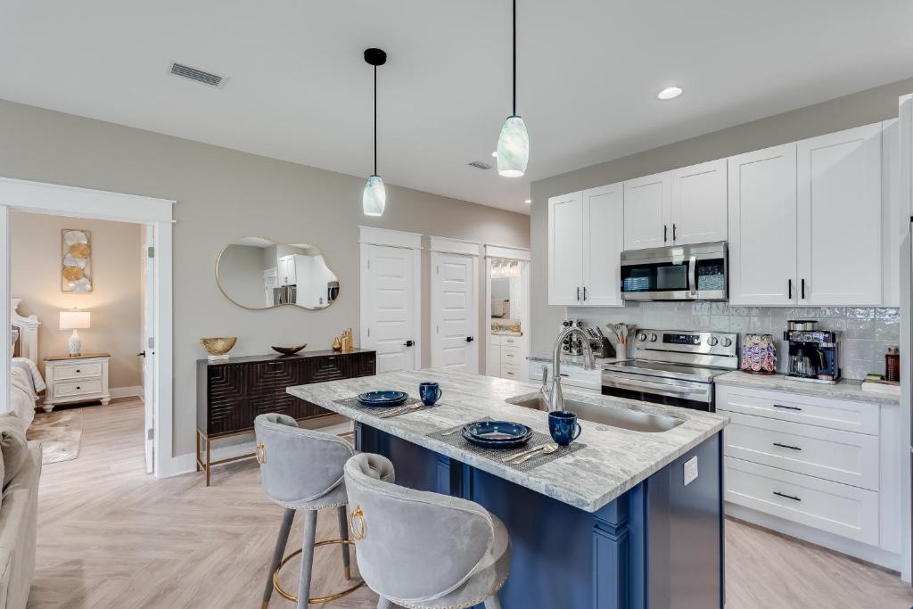 a kitchen with white cabinets and a blue island with chairs at Luxury Retreat near St. Andrews in Panama City Beach