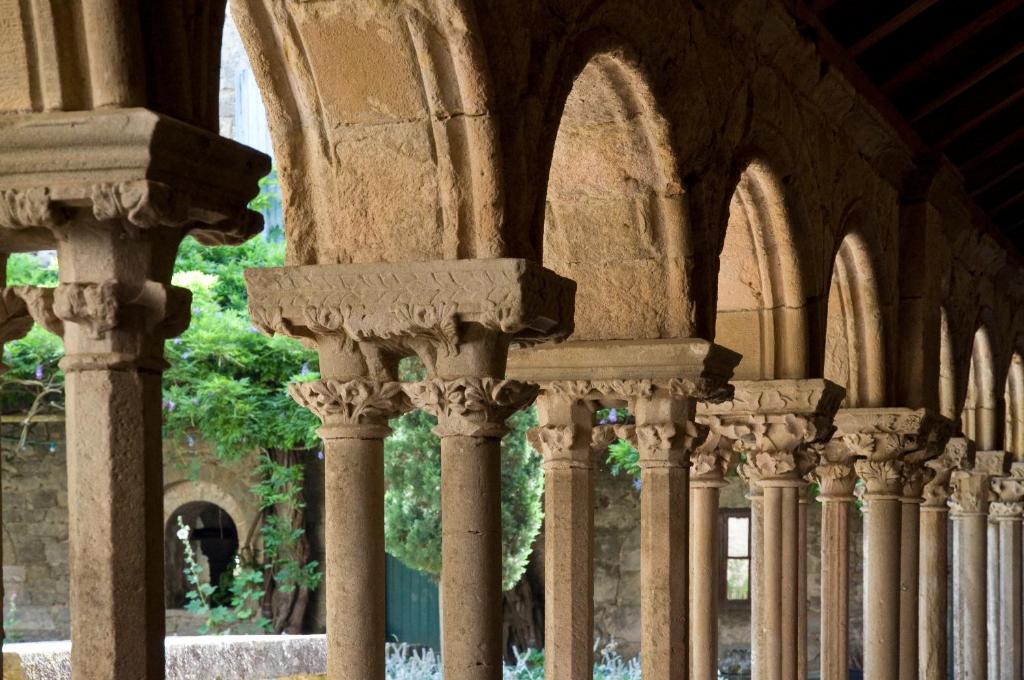 una fila de columnas en un edificio con arcos en Abbaye De Villelongue, en Saint-Martin-le-Vieil