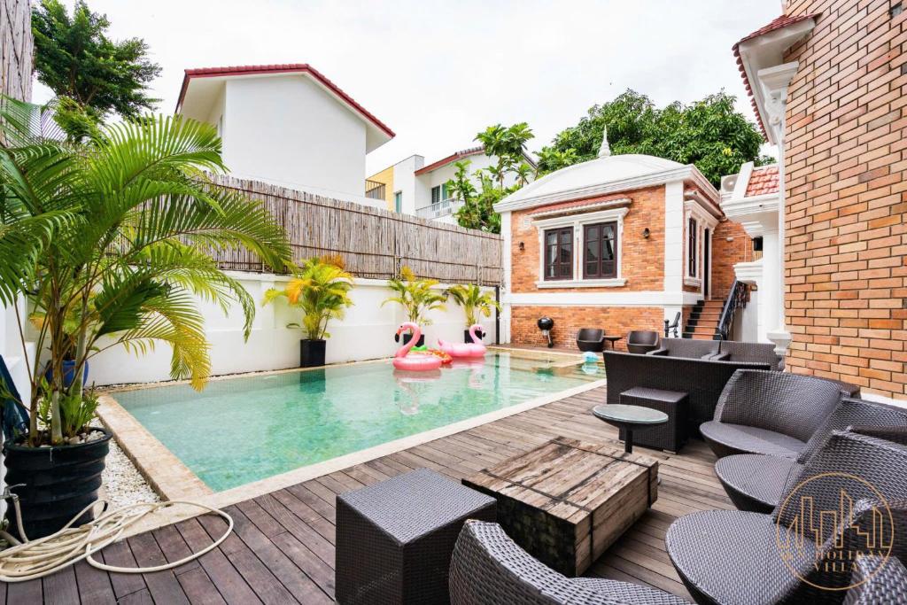 a backyard with a swimming pool with furniture and a house at KN 2 Villa - Venuestay in Ho Chi Minh City