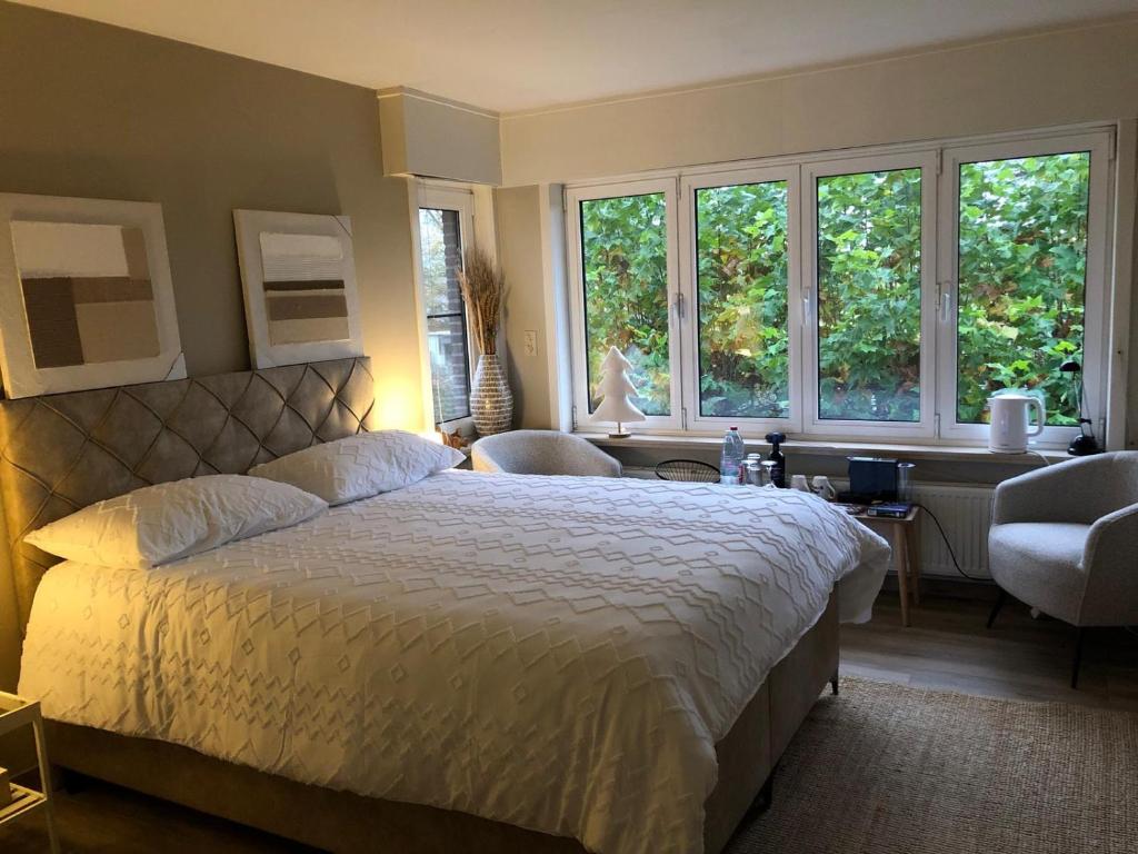 ein Schlafzimmer mit einem großen Bett und zwei Fenstern in der Unterkunft The Cozy Cottage in Eeklo