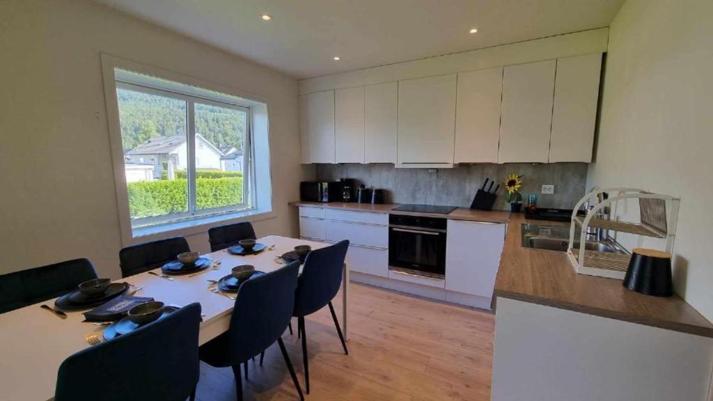 Una cocina con mesa y sillas y una cocina con gabinetes blancos. en Aalesund Guesthouse 4 Bedroom, en Ålesund
