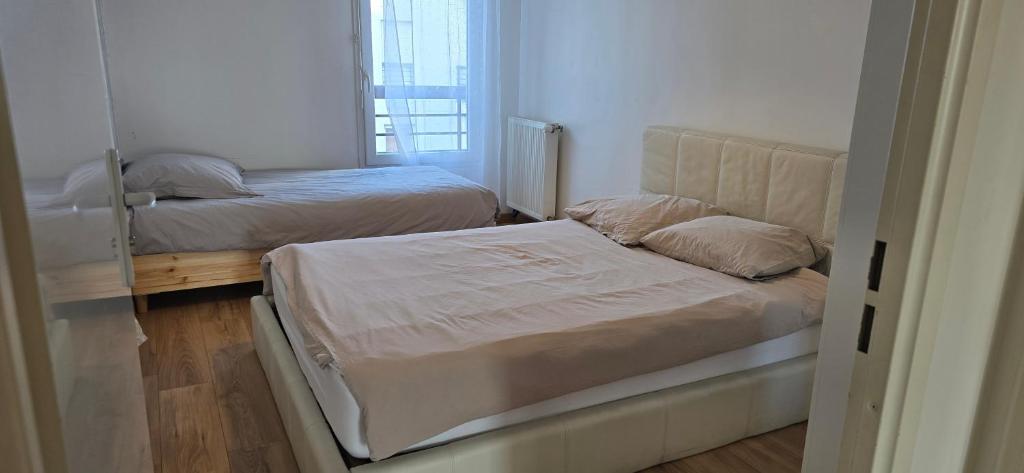a small bedroom with two beds and a window at Bel appartement près du métro in Saint-Denis
