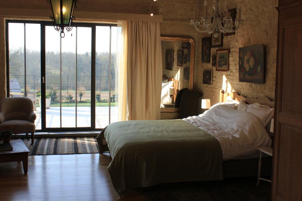 een slaapkamer met een bed en een groot raam bij La Passiflore B&B in Bossière