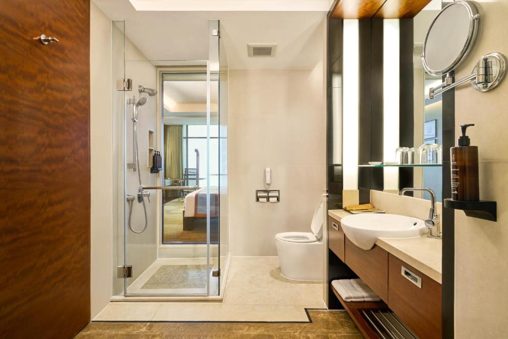 A modern bathroom with a glass-enclosed walk-in shower and separate toilet.