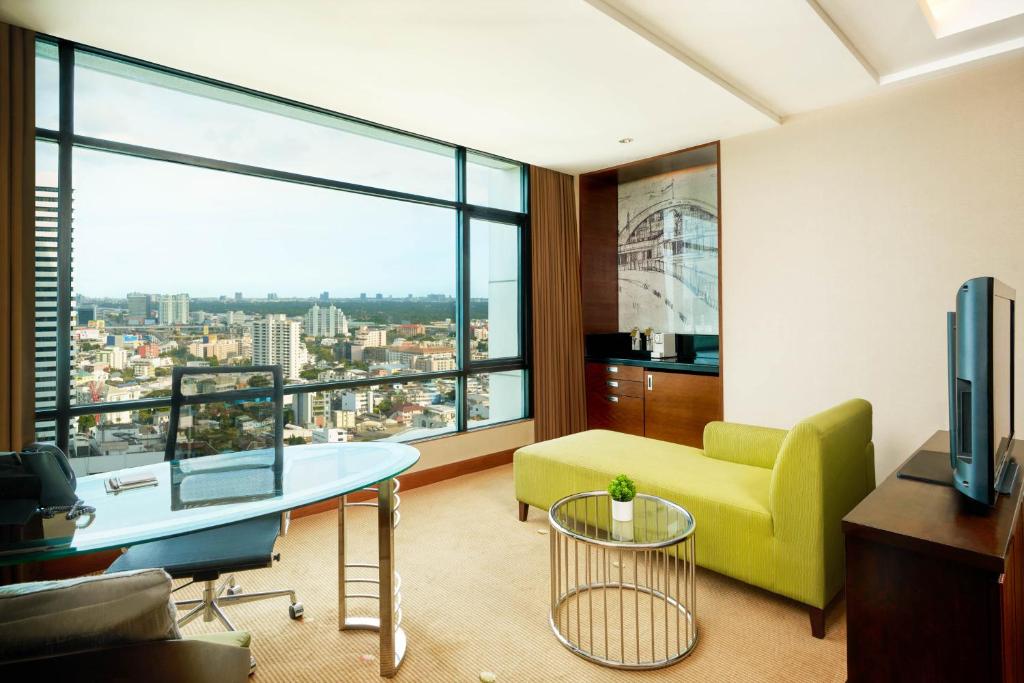 A sitting and work area with a lime-green sofa, glass desk and expansive urban outlook.