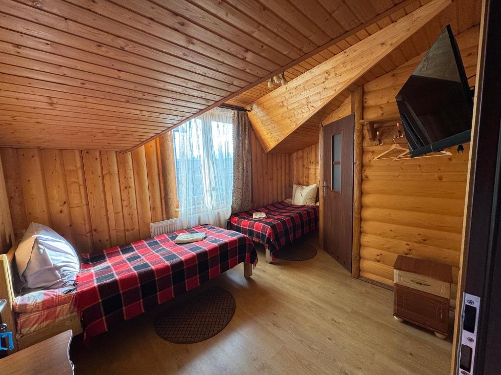 a room with two beds in a log cabin at Опришок in Palyanytsya