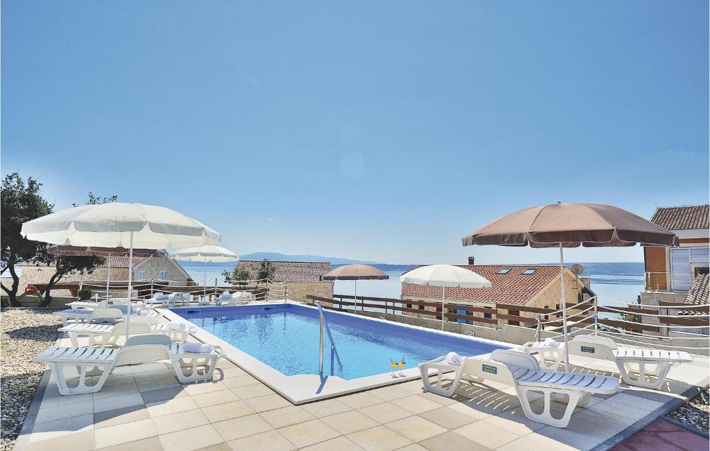 una piscina con sillas blancas y sombrillas en Apartment Pavlinka Bb Iii, en Posedarje
