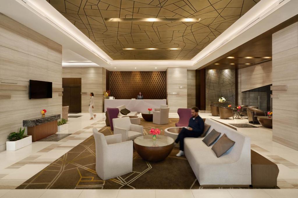 A polished lobby lounge with sofas, armchairs and a reception desk.