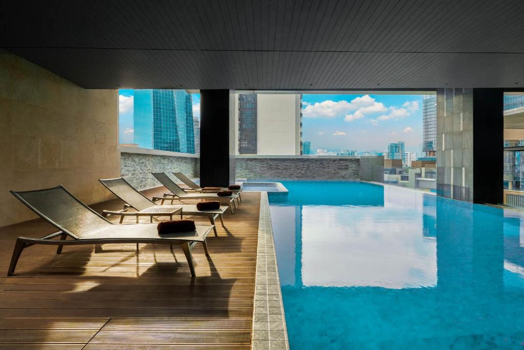 A covered rooftop pool with loungers and a wide city view.