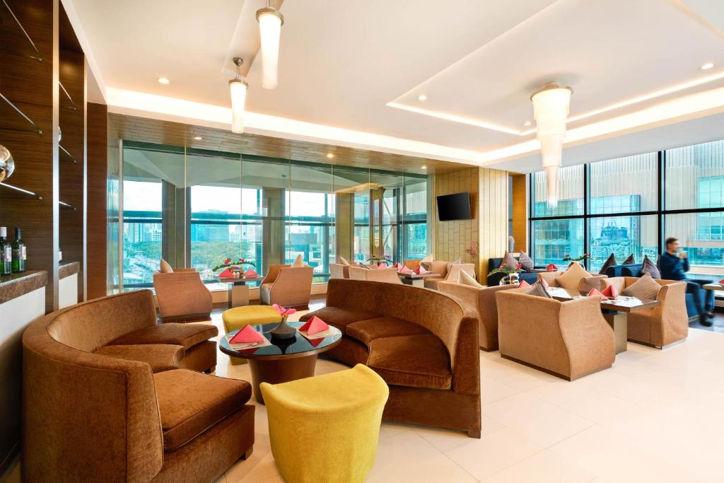 A spacious hotel lounge with clustered armchairs, sofas and floor-to-ceiling windows.