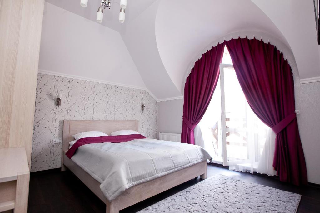 a bedroom with a bed with purple curtains and a window at Hotel Marsen in Vinnytsya