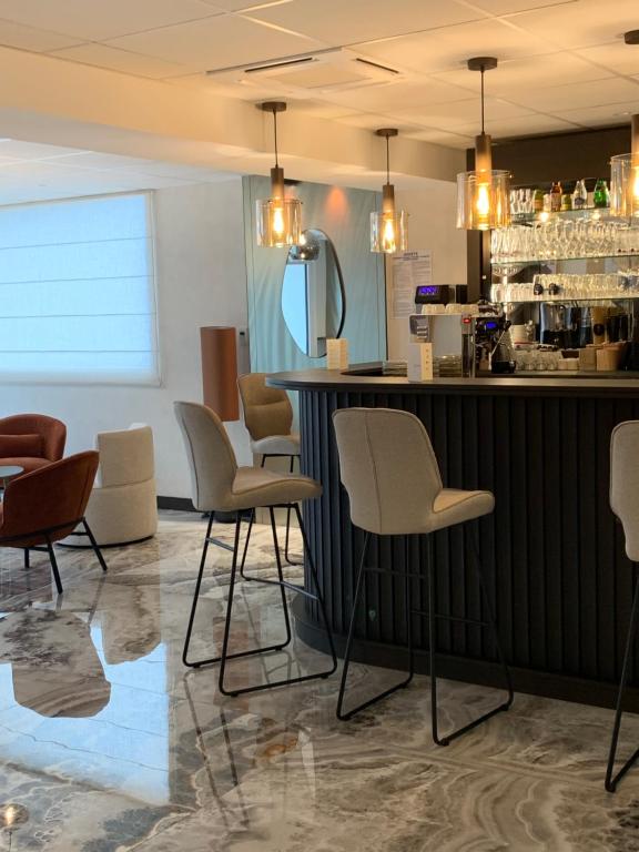 a bar in a restaurant with chairs and a counter at Hôtel Breizh Du Golfe in Arzon
