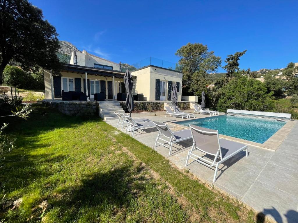 una casa con piscina y 2 sillas de césped en Villa de standing, en Calvi