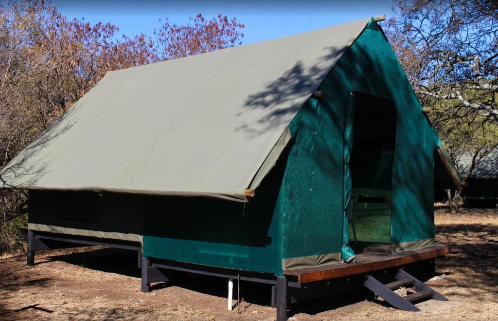 a green and white tent sitting in a field at Indabushe Eco Lodge in Schoemanskloof