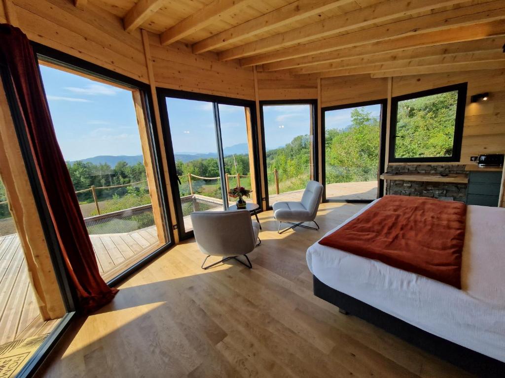 a bedroom with a bed and large windows at Cocooon Wood, hébergement insolite Savoie in Saint-Paul-sur-Yenne