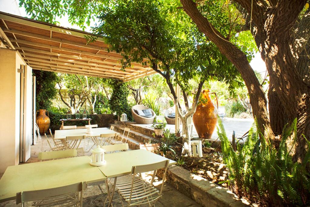 un patio avec tables et chaises sous une pergola en bois dans l'établissement Wp RELAIS LOCANDA FIORE DI ZAGARA, à Diso